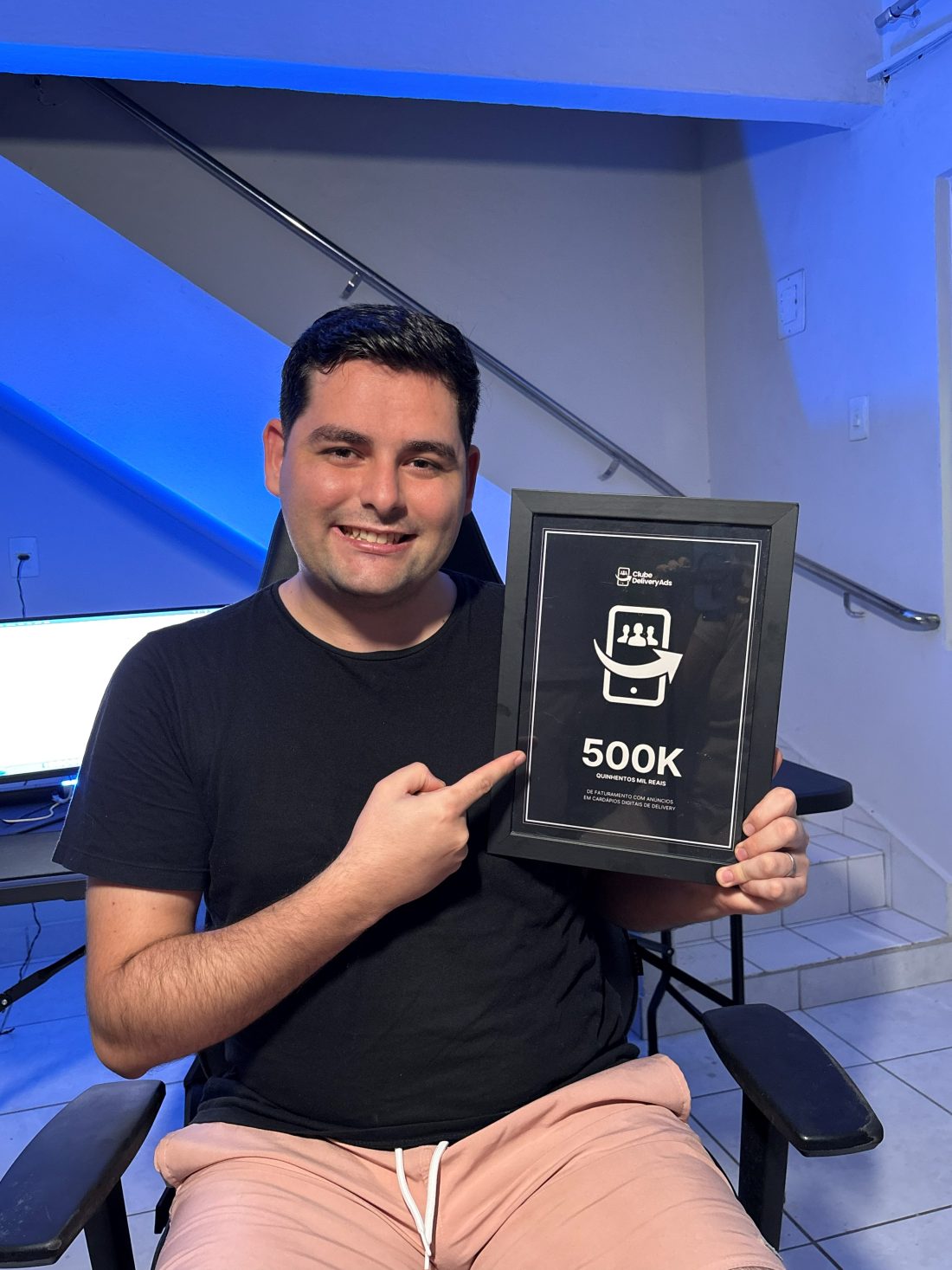 Guilherme Kemerich apontando para a placa de R$500 mil de faturamento gerado para deliveries